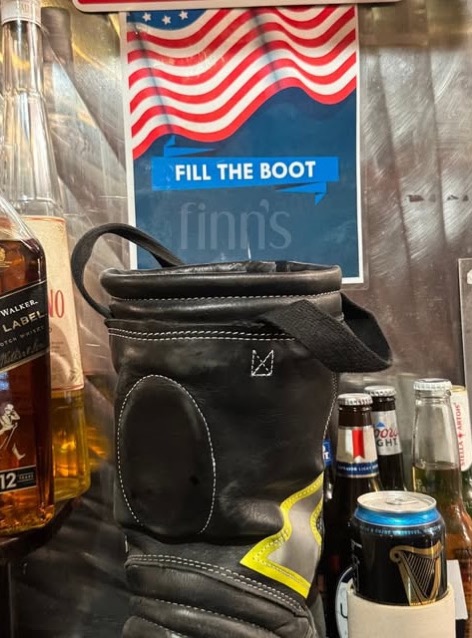 A firefighter’s boot set out on the bar for donations under a Fill the Boot sign