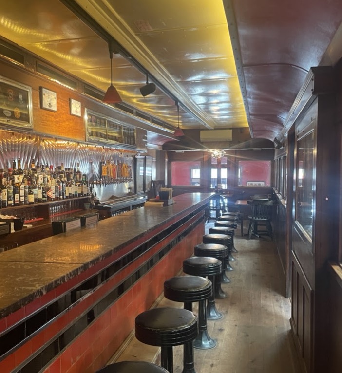 The empty diner car counter with black stools under its curved ceiling