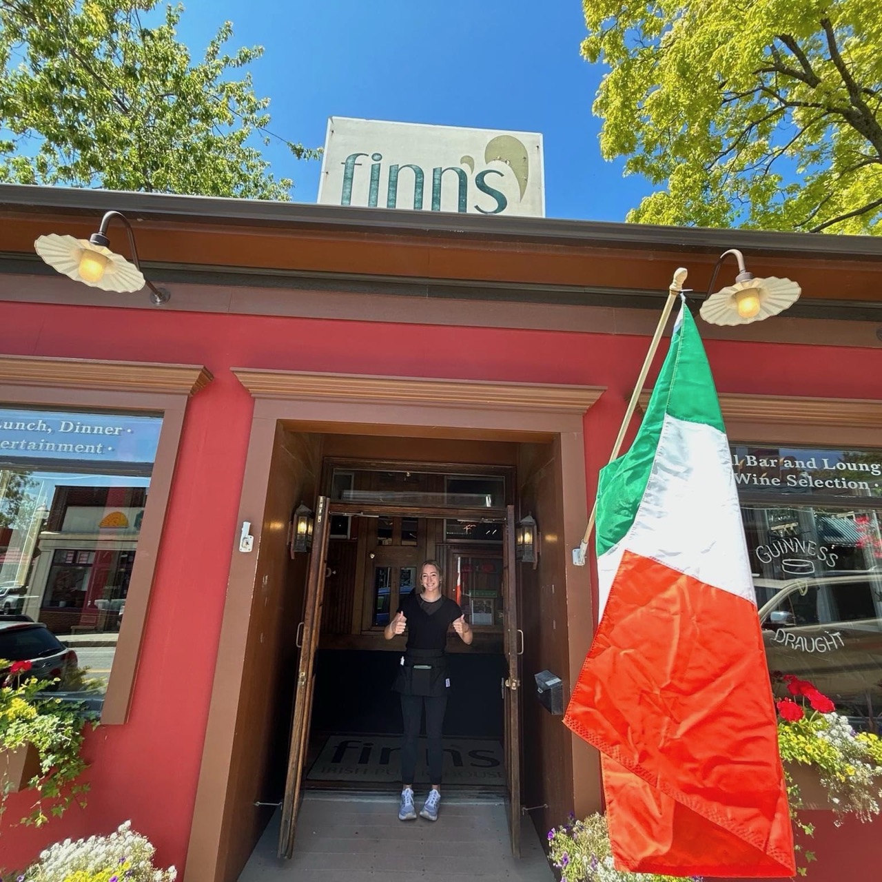 Finn’s red entrance on a sunny day, with an Irish flag beside the door and the rooftop sign above